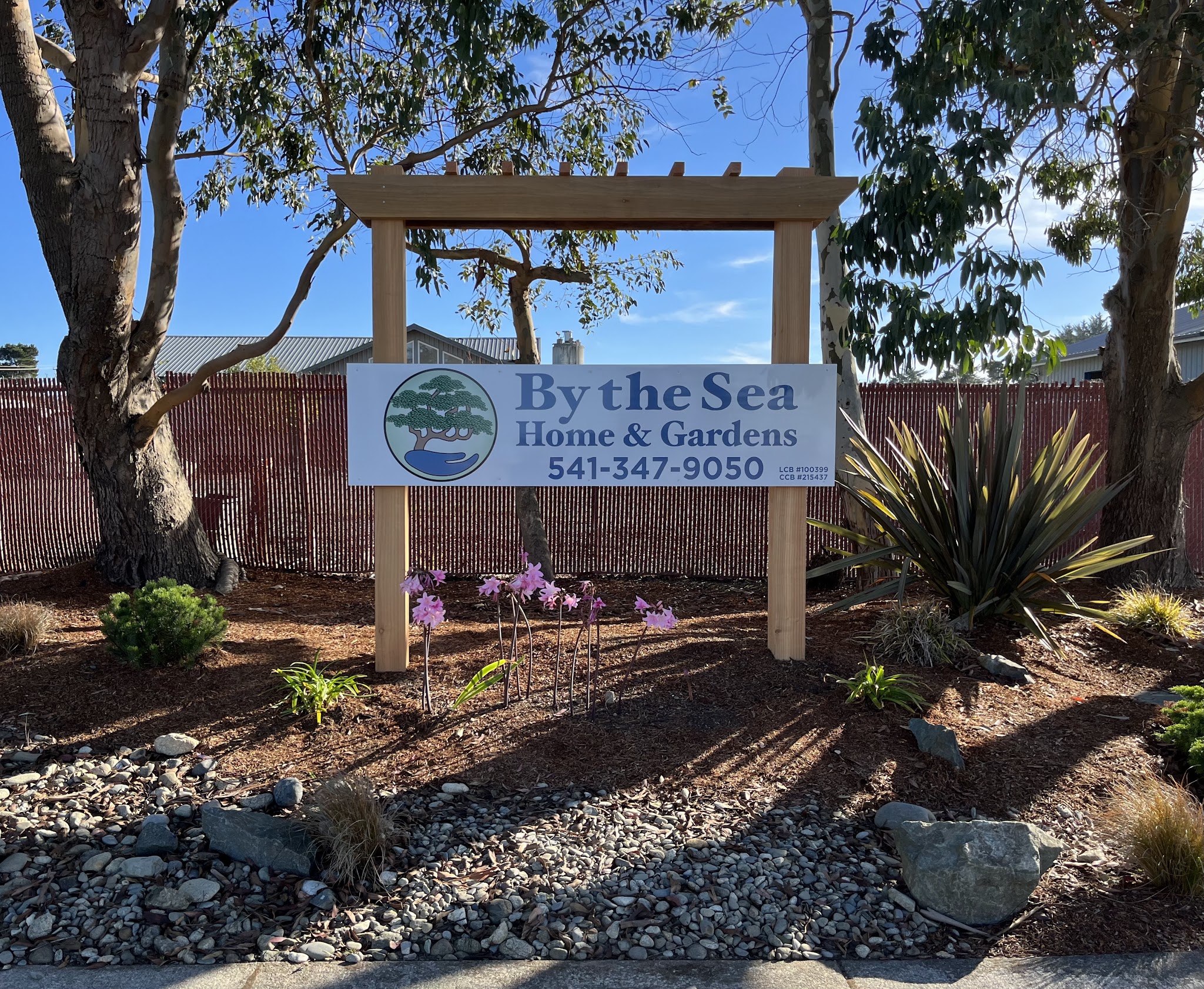 By the Sea Home & Gardens yard sign showing the company logo, phone number and Oregon CCB and LCB license numbers