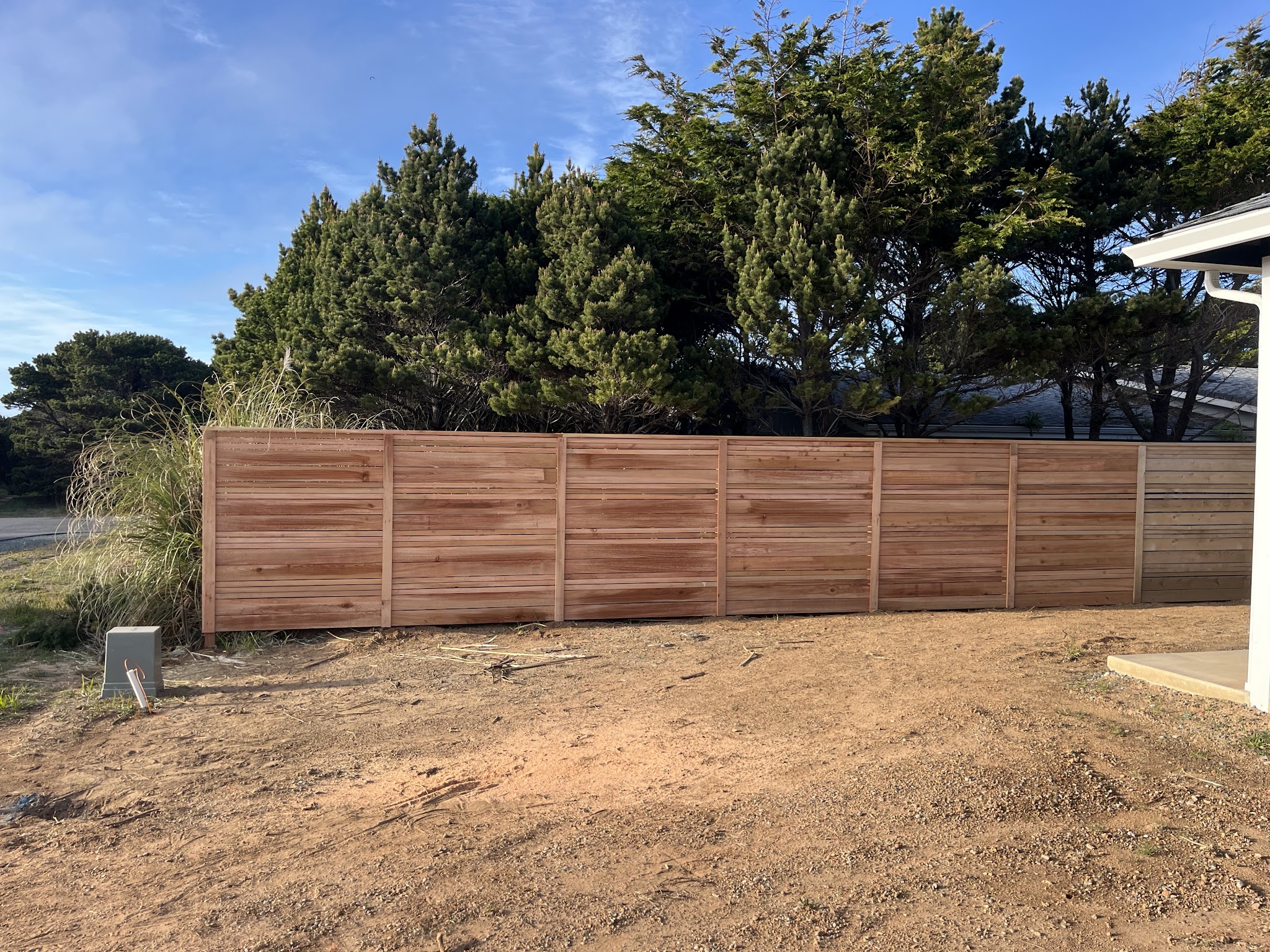 Horizontal-slat cedar privacy fence installation along a property line in Bandon, Oregon